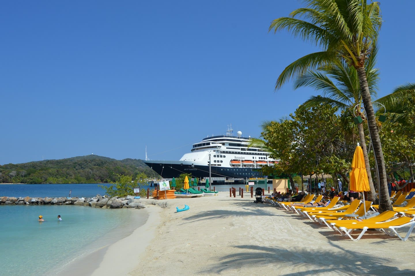 Crucero atracado en una playa tropical con gente relajándose.